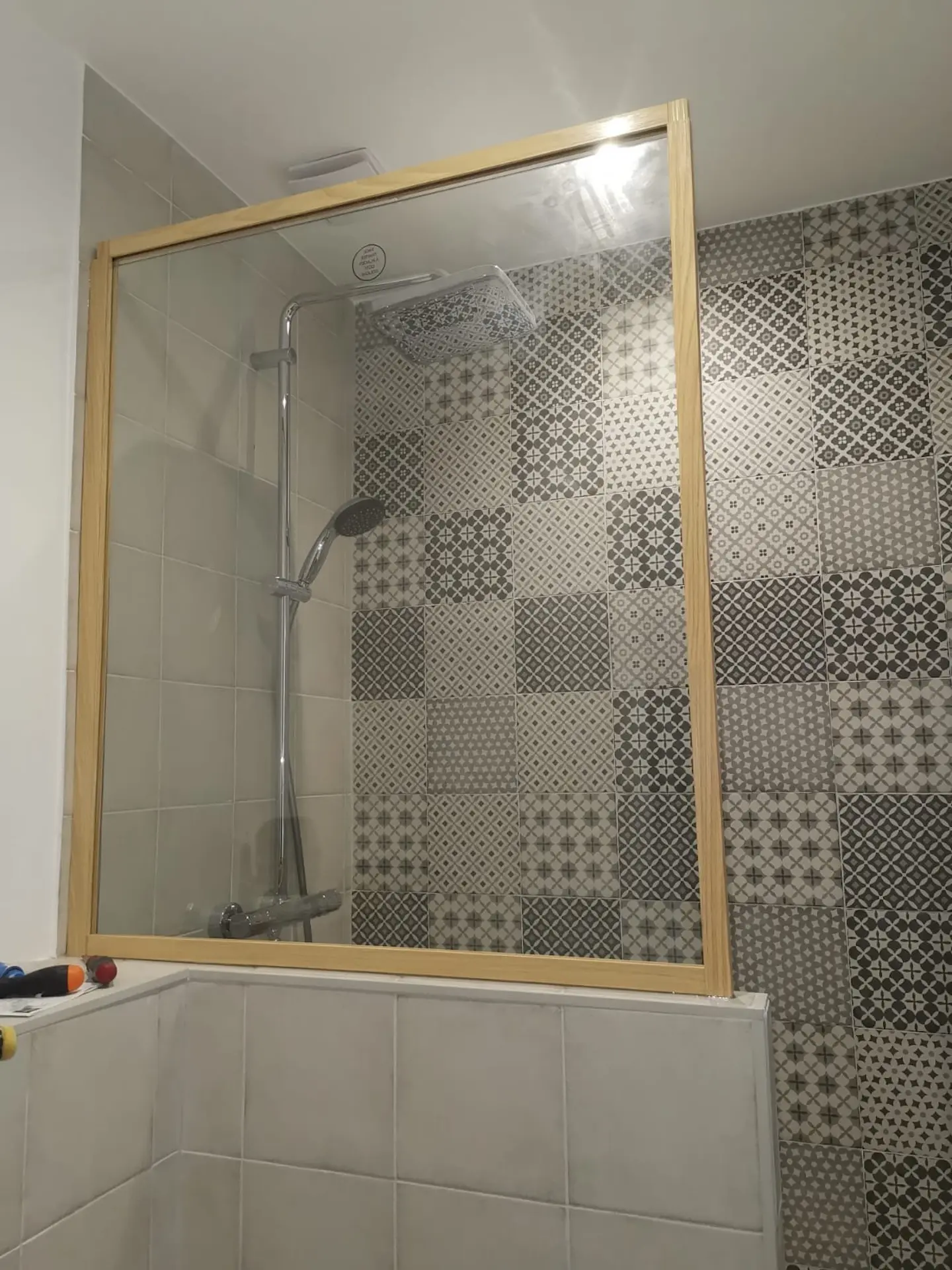 Douche avec carreaux ciment à motifs et encadrement bois sur baignoire