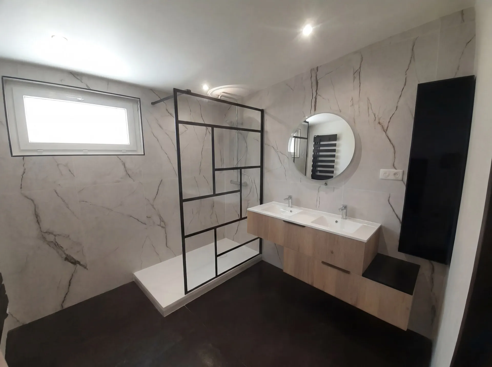 Salle de bains rénovée avec douche italienne, paroi industrielle noire et murs marbre veiné