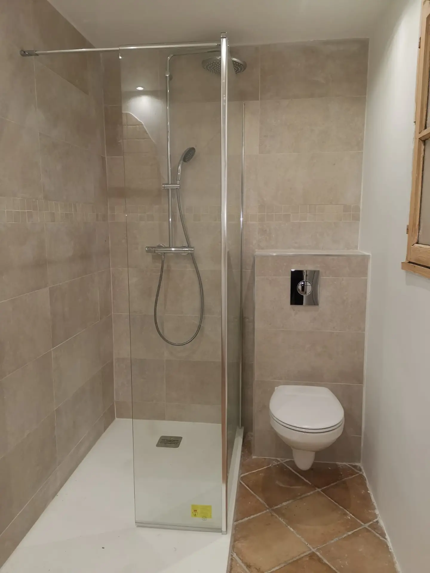 Colonne de douche pluie chromée sur carrelage gris travaillé
