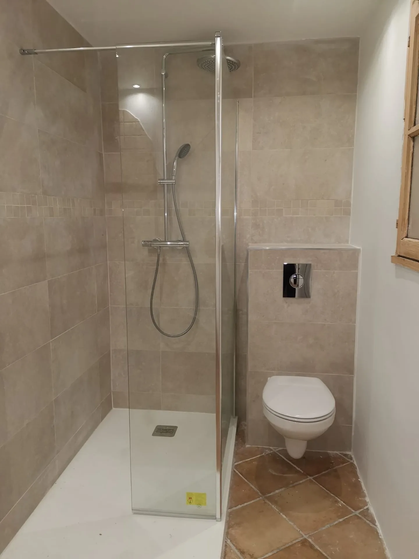 Colonne de douche pluie chromée sur carrelage gris travaillé