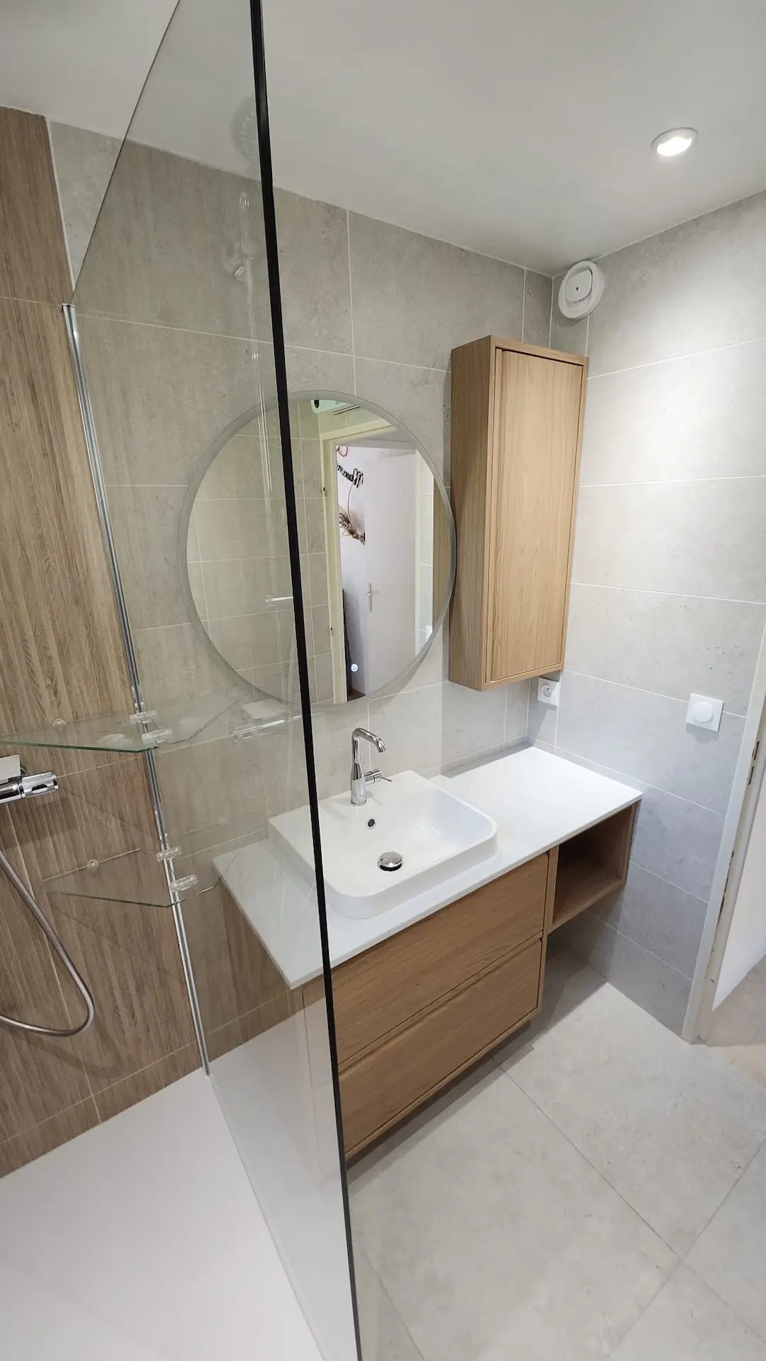 Salle de bains complète moderne avec meuble vasque bois suspendu, miroir rond et douche italienne