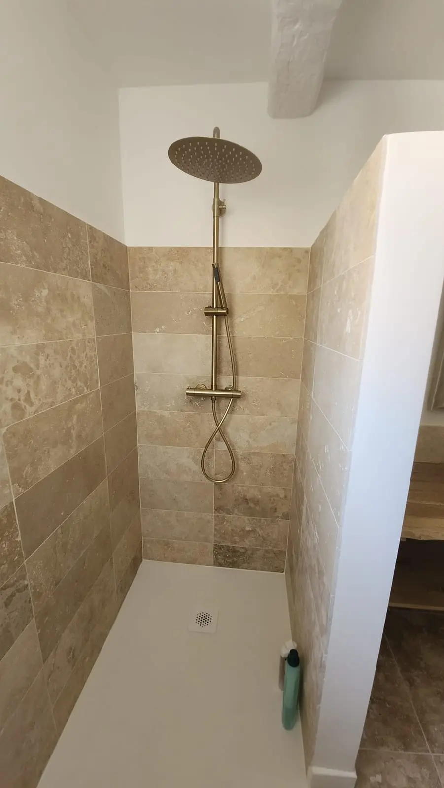 Douche à l'italienne habillée de travertin beige avec colonne de douche pluie en laiton brossé et receveur extra-plat blanc